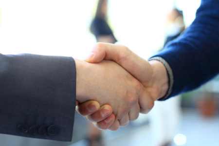 businesss and office concept – two businessmen shaking hands in